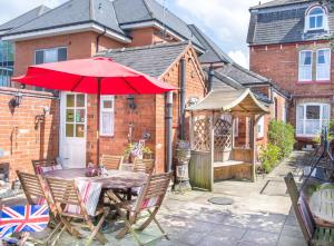 un tavolo e sedie con ombrellone rosso su un patio di Creston Villa Guest House a Lincoln