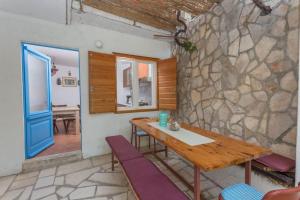 a room with a wooden table and a stone wall at Robinson Erina in Zarače