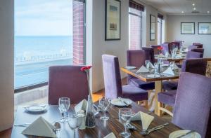 ein Restaurant mit Tischen und Stühlen und Meerblick in der Unterkunft Grand Hotel Blackpool in Blackpool