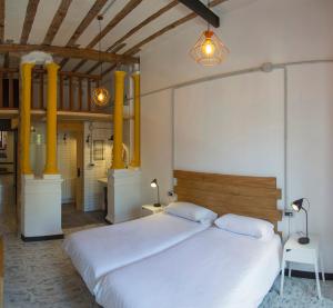 a bedroom with a large white bed and yellow columns at Green River Hostel in Cuenca