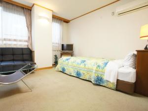 sypialnia z łóżkiem i krzesłem w obiekcie Hotel Trend Saijo w mieście Saijo