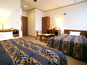 Habitación de hotel con 2 camas y escritorio en Hotel Trend Saijo en Saijo
