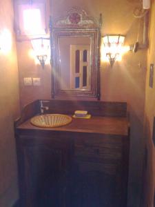 a bathroom with a sink with a mirror and lights at Auberge Des Jardins du Dades in Boumalne