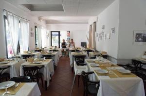 a dining room with white tables and chairs and people at Hotel Annarita-mezza pensione plus- spiaggia inclusa in Rimini