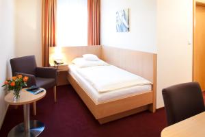 a bedroom with a bed and two chairs and a table at Hotel Clemenswerther Hof in Sögel