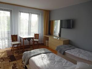 sypialnia z dwoma łóżkami, stołem i telewizorem w obiekcie Lenadia w Dziwnowie