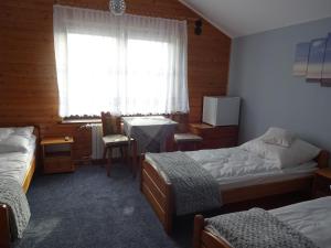 sypialnia z dwoma łóżkami, stołem i oknem w obiekcie Lenadia w Dziwnowie