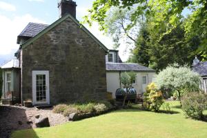 uma antiga casa de pedra com um jardim em frente em Glenalbyn Cottage em Saint Fillans