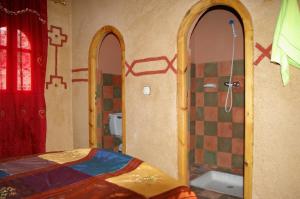a room with a bathroom with two mirrors and a shower at Auberge Des Jardins du Dades in Boumalne