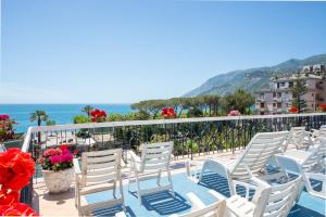 a row of white chairs on a balcony with the ocean at La Residenza Aparthotel in Maiori