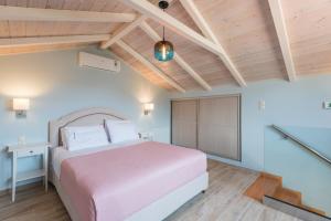 a bedroom with a pink bed and wooden ceilings at Pansion Ermioni in Skala