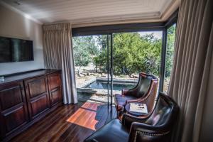 a living room with two chairs and a sliding glass door at The Royal Fischer Hotel in Bloemfontein