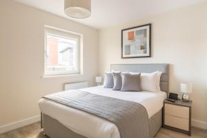 um quarto com uma grande cama branca com almofadas brancas em House of Fisher- Solstice House Apartments em Farnborough