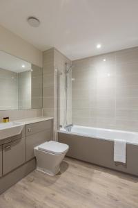 a bathroom with a toilet and a tub and a sink at House of Fisher- Solstice House Apartments in Farnborough