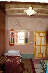a bedroom with a bed and a window and a chandelier at Auberge Des Jardins du Dades in Boumalne
