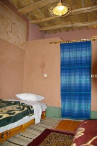 a bedroom with two beds and a blue curtain at Auberge Des Jardins du Dades in Boumalne
