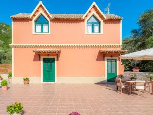 a house with green doors and a patio at Pieros Studios Lisipios in Paleokastritsa