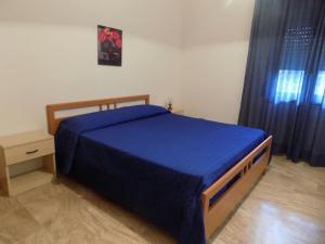 a bedroom with a bed with a blue bedspread and a table at Appartamenti Alessio in Girasole