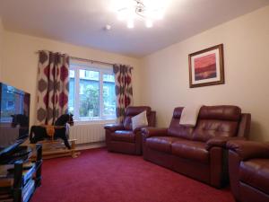 a living room with a couch and chairs and a tv at The Paddock Guest House in Keswick