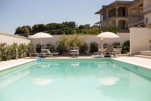 a swimming pool with chairs and umbrellas next to a building at Villa Del Mare in Alcamo Marina