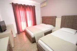 a hotel room with two beds and a television at Julia Hotel in Sarandë