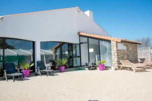 a patio with chairs and a table and a building at Hôtel des Dunes Noirmoutier in La Guérinière