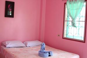 a bedroom with pink walls and a bed with a window at Dahla House Ranong in Ranong