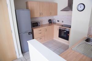 a kitchen with wooden cabinets and a refrigerator at East Village City Center Luxury Apartment in Liverpool