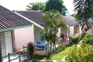 a row of cottages with palm trees and plants at Dahla House Ranong in Ranong