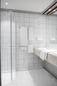 a white tiled bathroom with a shower and a sink at Vejle Center Hotel in Vejle