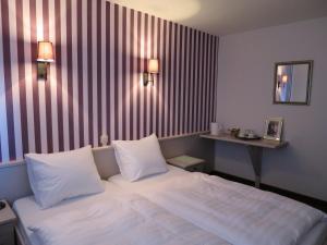 a bedroom with a large white bed with two pillows at Golf Hotel Mergelhof in Gemmenich