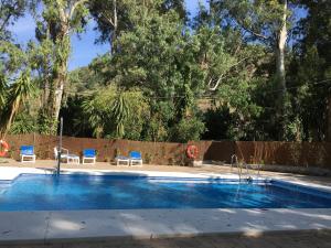 a swimming pool with two blue chairs and a fence at Hotel del Balneario in Tolox