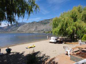 a sandy beach with a boat on the water at Bella Villa Resort Motel in Osoyoos