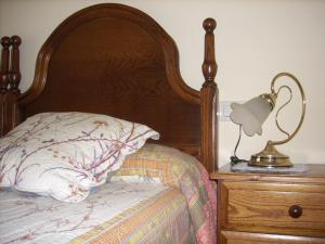 a bed with a wooden headboard and a lamp on a dresser at Pension Txomin Ostatua in Etxebarria