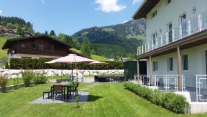 eine Terrasse mit Tischen und einem Sonnenschirm neben einem Gebäude in der Unterkunft Apartment Haus Van der Leij in Russbach am Pass Gschütt