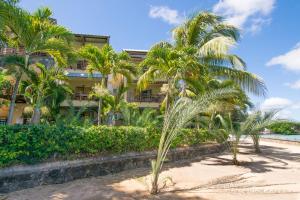 een gebouw op het strand met palmbomen bij Residence Peramal in Grand Baie