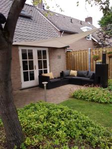 un patio trasero con sofás y una valla en B&B Eeneind en Nuenen