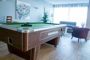 a room with a pool table in a living room at Hôtel des Dunes Noirmoutier in La Guérinière