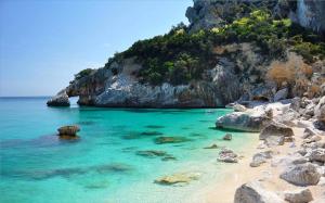 a beach with blue water and a rocky cliff at Appartamenti Alessio in Girasole