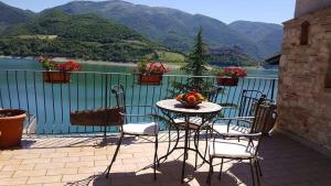 uma mesa e cadeiras numa varanda com vista para um lago em B&B La Casetta sul Lago em Colle di Tora