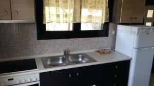 eine Küche mit einer Spüle und einem weißen Kühlschrank in der Unterkunft Giorgos Garden House in Keramotí