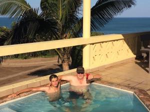 two men in a swimming pool with the ocean in the background at Go Wild Resort in Xai-Xai
