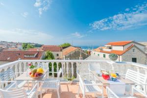 a balcony with white chairs and a table with fruit on it at Apartments Roma in Baška Voda