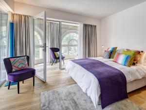 a bedroom with a large bed and a purple chair at Hotel Anker Luzern in Luzern