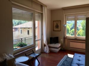 ein Wohnzimmer mit zwei großen Fenstern und einem TV in der Unterkunft Il Vecchio Teatro in Biella
