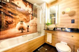 a bathroom with a bath tub, toilet, and sink at Leonardo Royal Edinburgh Haymarket in Edinburgh