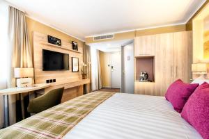 a hotel room with a bed and a television at Leonardo Royal Edinburgh Haymarket in Edinburgh