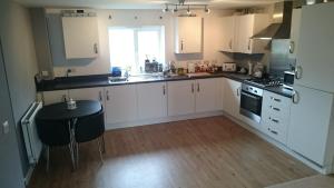 ミルトン・キーンズにあるModern Apartment in Milton Keynesの白いキャビネットとテーブル付きのキッチンが備わります。