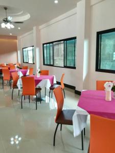 uma sala de jantar com mesas e cadeiras cor-de-rosa e janelas em Sakura Budget Hotel em Hat Yai