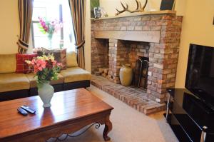 a living room with a brick fireplace and a coffee table at Culzean House in Ardentinny